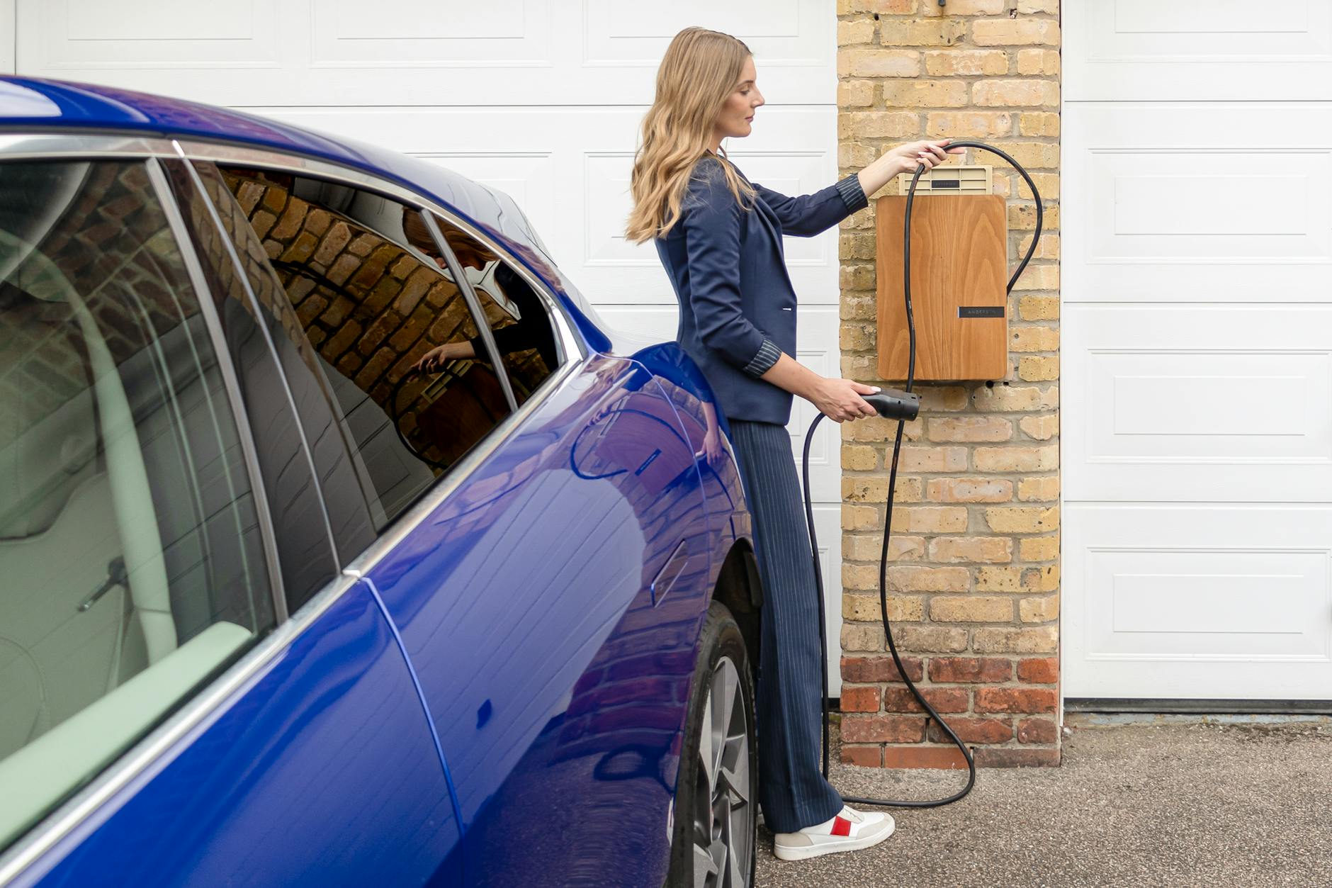 Kobieta ładująca niebieskiego elektrycznego BYD przy domowej ładowarce
