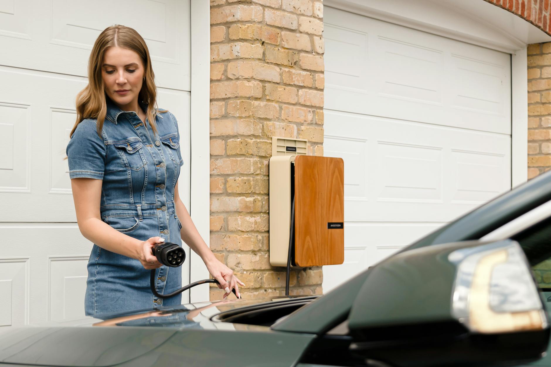 Kobieta podłącza ładowarkę do auta elektrycznego przy domowym wallboxie