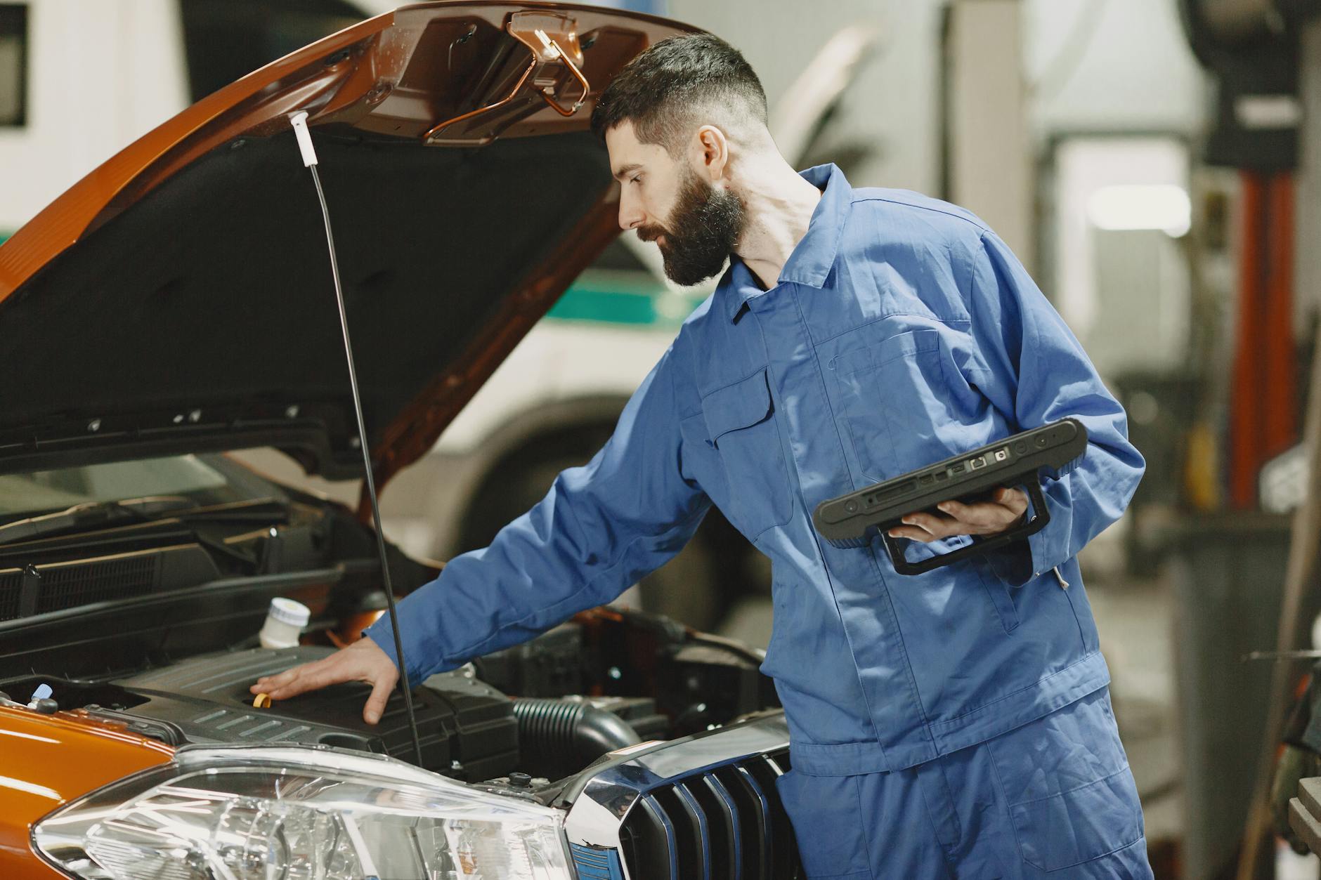 Mechanik sprawdza silnik Peugeota pod otwartą maską w warsztacie