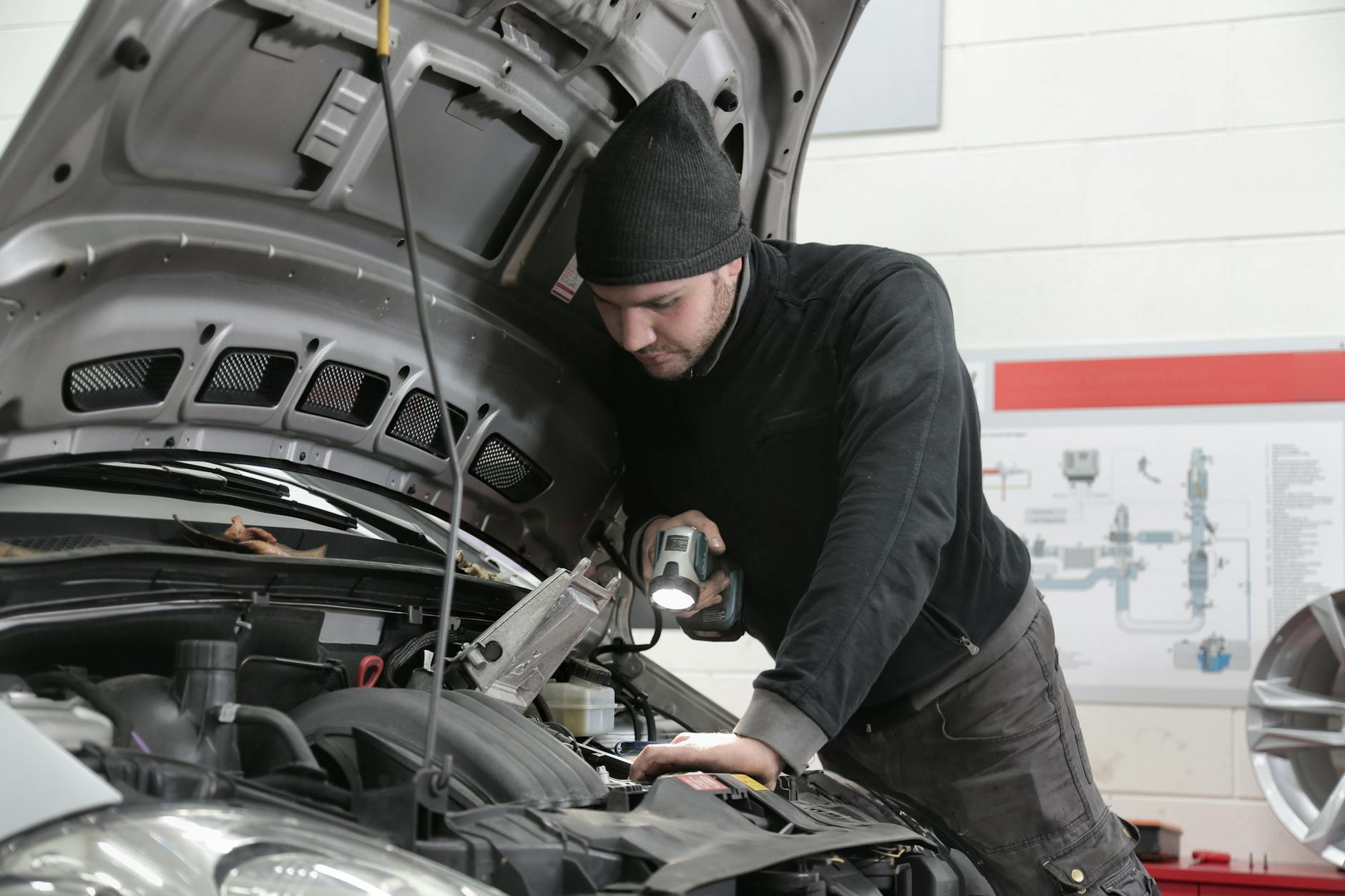 Mechanik z latarką dokładnie ogląda silnik samochodu w warsztacie