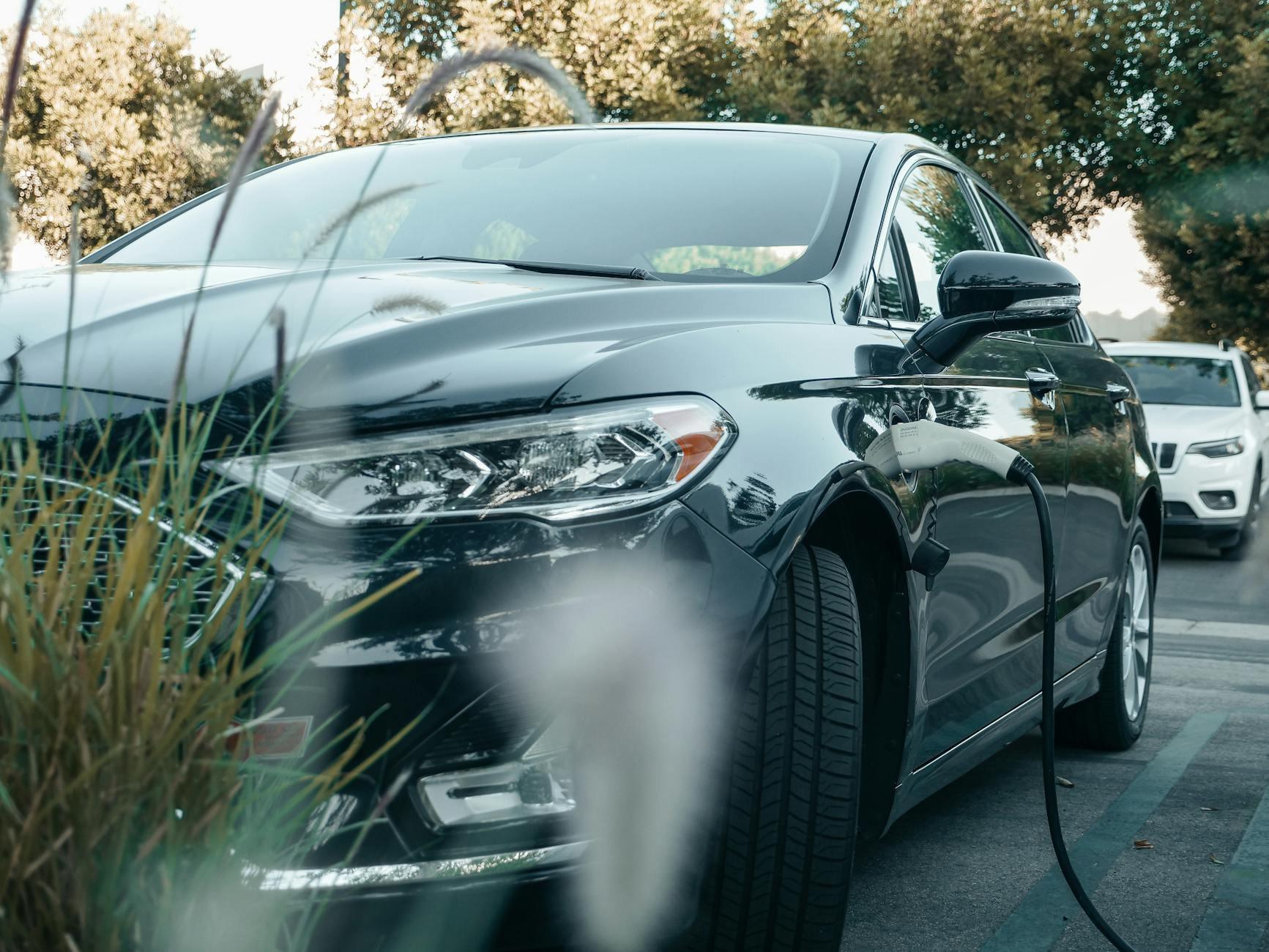Czarny hybrydowy Citroën C5 X ładowany na zewnętrznej stacji wśród zieleni