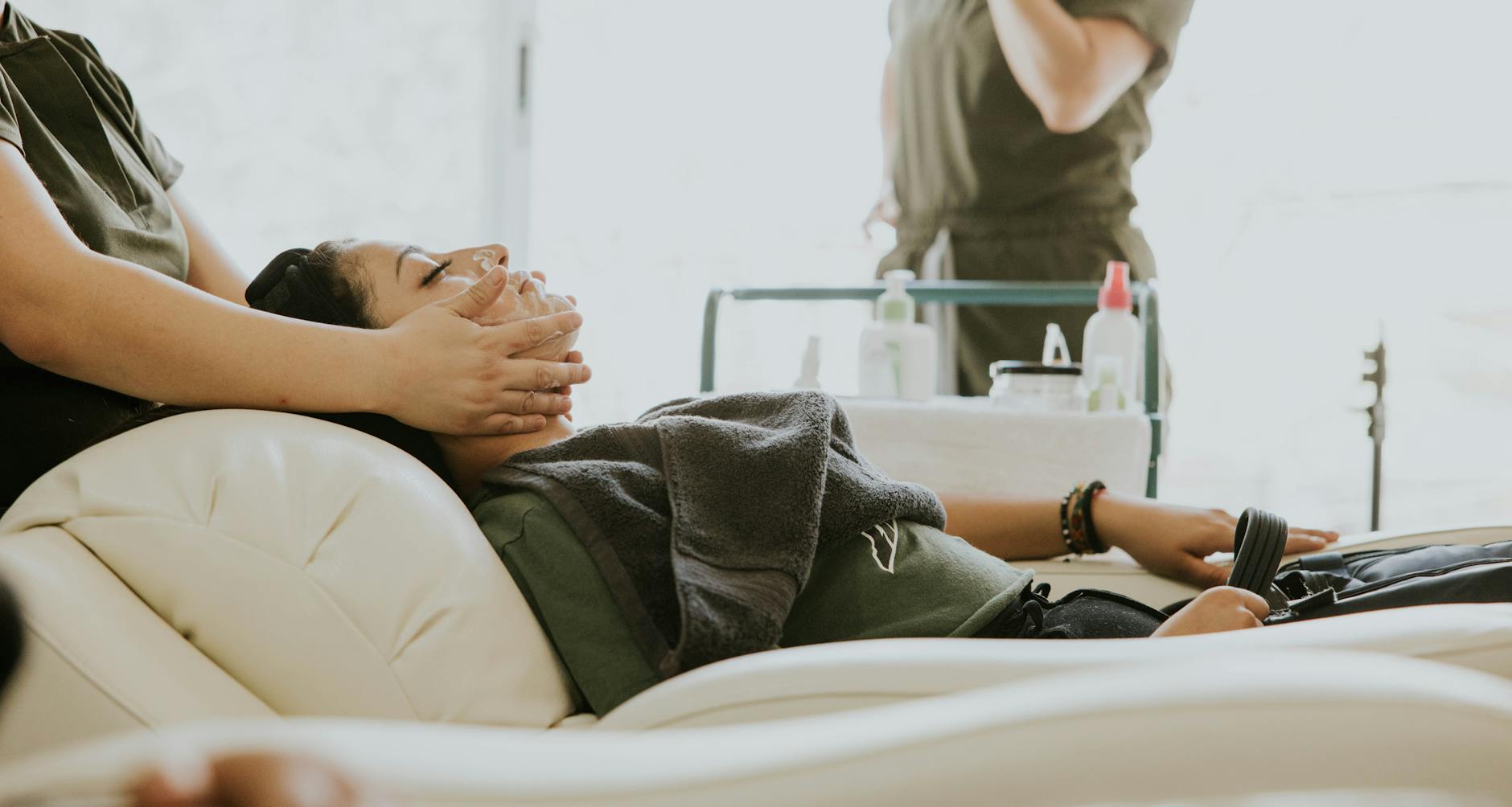 Kobieta podczas relaksacyjnego masażu twarzy w gabinecie spa