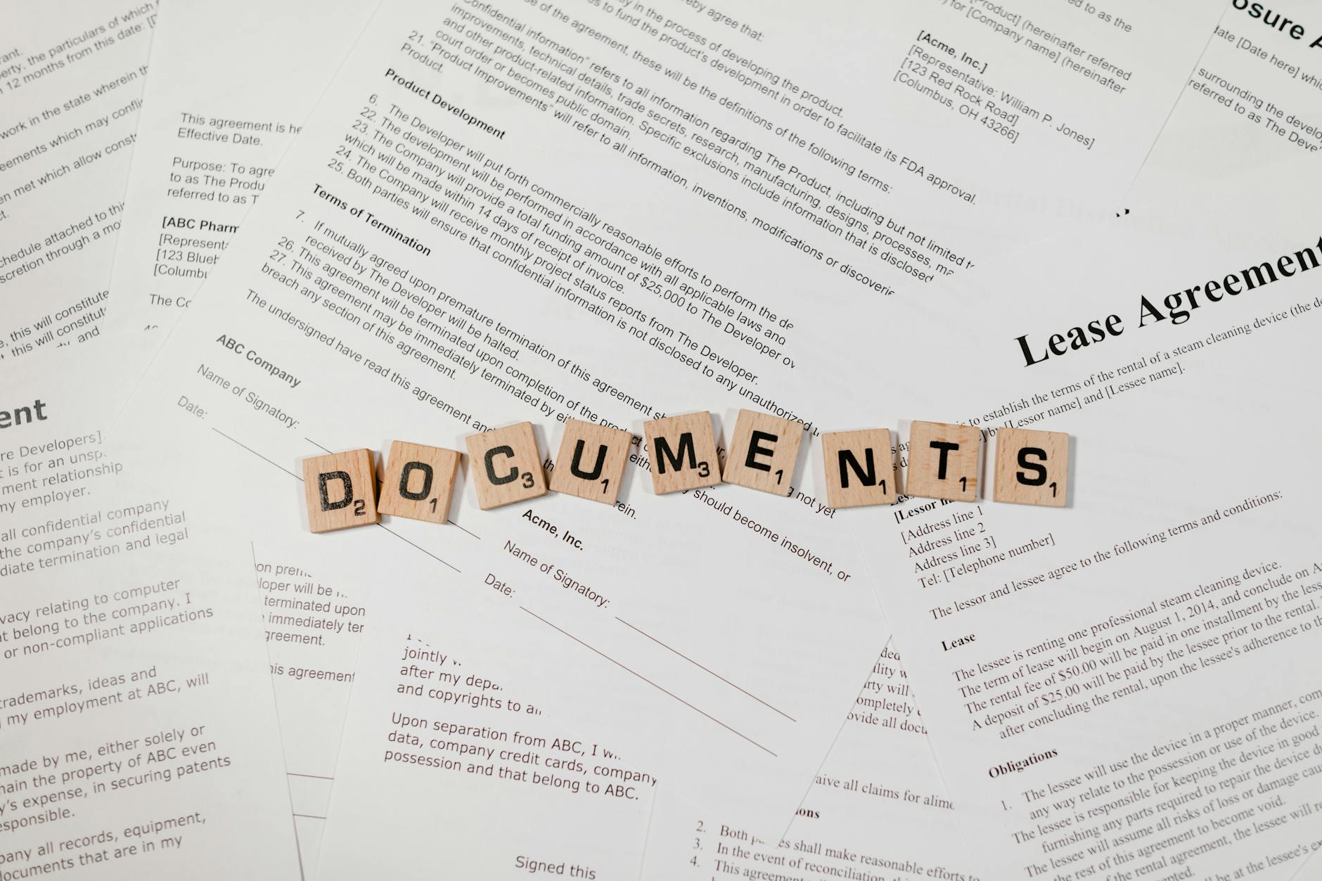 Kafle scrabble układające się w słowo DOCUMENTS na stosie umów