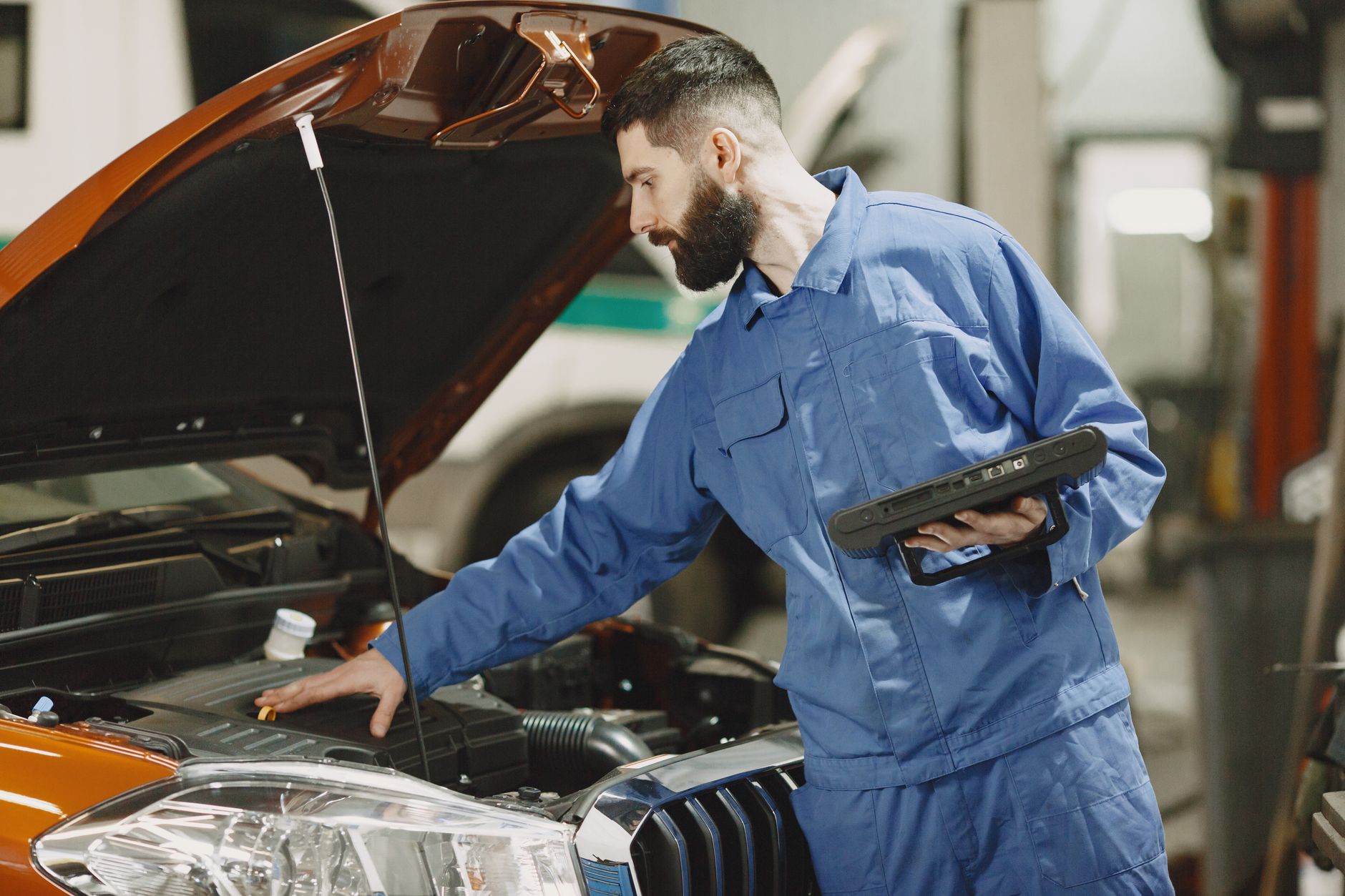 Mechanik sprawdza silnik Peugeota pod otwartą maską w warsztacie